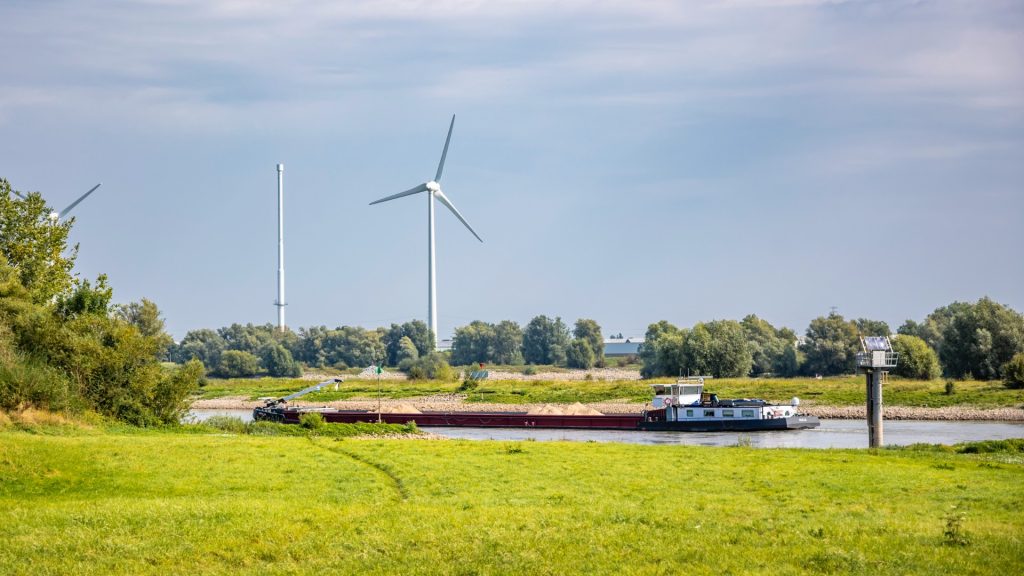 vrachtschip over de IJssel met in de achtergrond een windmolen